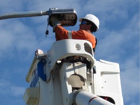 A city worker installs an LED streetlamp.