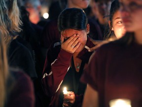 A woman cries during a candlelight vigil for the victims of the Wednesday shooting at Marjory Stoneman Douglas High School, in Parkland, Fla., Thursday, Feb. 15, 2018. Nikolas Cruz, a former student, was charged with 17 counts of premeditated murder on Thursday.