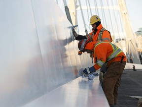 Workers undertake some final clean up on the new Walterdale Bridge's Shared Use Path before it opens to the public on Dec. 21 in Edmonton, Alberta on Wednesday, December 20, 2017.