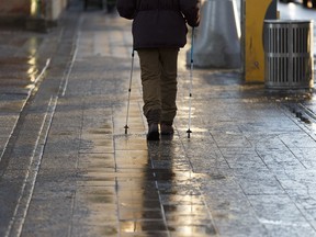 Wayne Kanak uses some good boots and his walking poles to navigate slippery sidewalks along Jasper Avenue after overnight freezing rain in Edmonton, Alberta on Wednesday, Jan. 17, 2018.