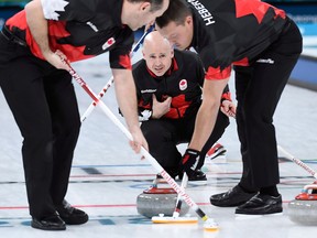 Canada skip Kevin Koe plays a stone as second Brent Laing, left, and lead Ben Hebert sweep during men's semifinal curling action against the U.S. at the Pyeongchang Olympics on Feb. 22, 2018