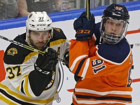 Edmonton Oiler Drake Caggiula (right) is checked by Boston Bruins Patrice Bergeron (left) during NHL game action in Edmonton on Tuesday February 20, 2018.
