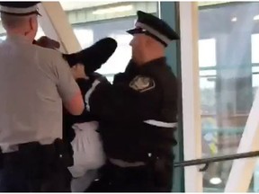 Screenshot of a video showing two transit peace officers detaining a 15-year-old boy at an Edmonton transit station. The boy's father said his son was a victim of racial profiling and excessive force.
