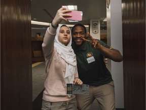 Edmonton Eskimos defensive lineman Kalonji Kashama takes a photo with Sally Rached, 15, during a Football 101 with an Immigration and Settlement Services youth group at Commonwealth Stadium, on March 26, 2018.