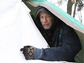 Frank Welsh, 46, peers out from between two tarps in what has been his home in a camp in Dawson Park on Friday, March 2, 2018. Welsh says he is waiting for long-term housing and is working with social services agencies, but until then his tents and tarps are his home.