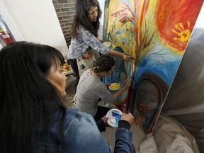 Artists Nancy Desjarlais, left, Tiffany Mayne and Florence Shone work on a piece encapsulating their experiences being involved in the Sixties Scoop at Amiskwaciy Academy as the Government of Alberta hears survivors' stories to craft an apology in Edmonton, Alta., on Thursday, March 1, 2018.