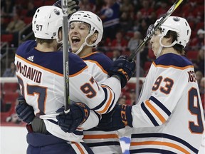 Edmonton Oilers' Matt Benning, center, is congratulated by Connor McDavid, left, and Ryan Nugent-Hopkins (93) following Benning's goal against the Carolina Hurricanes during the first period of an NHL hockey game in Raleigh, N.C., Tuesday, March 20, 2018.