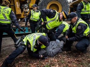 Dan Wallace, of the Kwakwaka'wakw First Nation on Quadra Island, is tackled and handcuffed by RCMP officers after attempting to talk to a young man that locked himself to a piece of heavy equipment being delivered to Kinder Morgan in Burnaby, B.C., on Monday March 19, 2018. Wallace was released a short time later without being charged. Numerous protesters who blockaded an entrance - defying a court order - were arrested earlier in the day while protesting the Kinder Morgan Trans Mountain pipeline expansion.