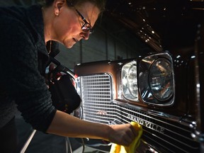 Tracy Drinnan uses a lamp as she cleans the grill of her and her husband's 1971 Pontiac Grand Ville convertible at the World of Wheels show which kicked on Friday at the Expo Centre in Edmonton, March 2, 2018.