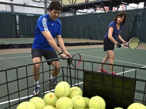 Ivan , a coach and tennis pro at the Saville Community Sports Centre, feeds tennis balls to new player Liane Faulder.