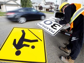 A city crew sets up signs for a 30 km/h playground zone on Haddow Drive in Edmonton on Sept. 15, 2017. Of the city's 163 playground zones, 68 are eligible for removal in a report slated to be discussed at a city council committee meeting on Wednesday, Aug. 15, 2018.