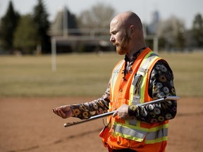 Travis Kennedy, general supervisor for open space operations for the city, checks the moisture content of a ground core sample at a baseball field near 133A Avenue and 87 Street, Wednesday, April 25, 2018.
