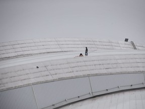 Workers examine a hole in top of the Rogers Centre as the area around the CN Tower is closed off due to reports of falling ice in Toronto on Monday, April 16, 2018.