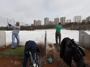 Rob Turner (left) and Barry Shymanski hit the driving range at Victoria Park Golf Course on a snowy spring opening day in Edmonton, on Friday, April 13, 2018.