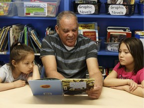 Retired school bus driver Hugh Derrick, centre, 72, reads the Magpie Song book to Chloe, left, 6, and Adriana, 9, at Prince Charles School in Edmonton, on Wednesday, April 18, 2018.