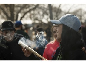 Revelers smoke a joint during the 4-20 marijuana rally at the Alberta legislature in Edmonton, on Friday, April 20, 2018.