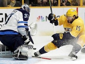 Winnipeg Jets goalie Connor Hellebuyck (37) blocks a shot from Nashville Predators right wing Craig Smith (15) during Game 1 of an NHL second-round playoff series Friday, April 27, 2018, in Nashville, Tenn. (AP Photo/Mark Humphrey)