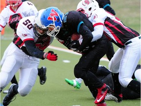 Grizzlies Duncan Houssian is tackled by Riley Mcnabb (l) and Keegan St. Denis in Capital District Minor Football Assoc. midget championships play at Foote Field in the Tier II game between the Mill Woods Grizzlies (in black) and the Battle River Shock (red and white) in Edmonton, May 4, 2014. File photo.