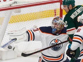 Edmonton Oilers goalie Cam Talbot, left, blocks a shot as Minnesota Wild forward Nino Niederreiter tries to bat the airborne puck into the net in the third period of an NHL game Monday, April 2, 2018, in St. Paul, Minn. The Wild won 3-0.