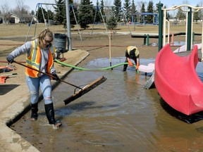 City of Edmonton employees Alyssa Myck, left, and Bill Sobotiuk work to pump excess water from Edmund Kelly Park playground in northeast Edmonton on Friday, April 20, 2018.