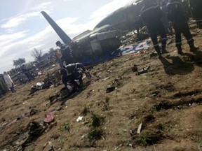 This image dated Wednesday, April 11, 2018, and posted by Algerian news agency ALG24, shows firefighters and soldiers at the scene of a fatal military plane crash near Boufarik military base near the Algerian capital, Algiers. At least 100 people were killed when a military plane carrying soldiers crashed soon after takeoff in a farm field in northern Algeria. ALG24 logo placed on photo at source. (ALG24 via AP)