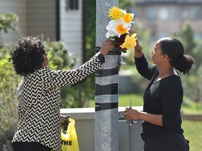 Members of Gary Yemane's family, wife Abeba Ghebregzabhir, left, and daughter Winta Berhane, place flowers at the location on Ozerna Road and 165 Avenue where Gary Yemane was killed two years ago.