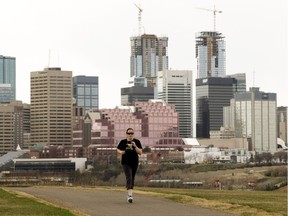 The city skyline is visible behind a jogger making their way along Strathearn Crescent, in Edmonton Wednesday May 2, 2018.