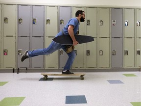 Daren Patterson carries an under-construction longboard as he rolls through the hall at Michael Strembitsky School, 4110 Savaryn Dr. SW, in Edmonton on Thursday, May 24, 2018. Students in Patterson's Grade 9 construction class have the option to build their own longboard during the course. Patterson will be leading a similar longboard making camp for Grade 7-9 students, through Metro Continuing Education in July.