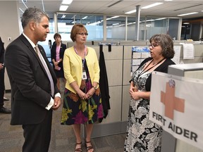 Community and Social Services Minister Irfan Sabir, left, and supervisor Betty Sulikowski speak with Alberta Supports Contact Centre co-ordinator Crystal Fisher after holding a news conference on the establishment of a centralized telephone line to help ensure Albertans concerned about abuse and neglect are connected to the right supports and services, in Edmonton on Monday, May 28, 2018.