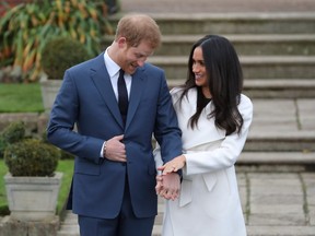 In this file photo taken on November 27, 2017 Britain's Prince Harry stands with his fiancée, actress Meghan Markle, as she shows off her engagement ring whilst they pose for a photograph in the Sunken Garden at Kensington Palace in west London on November 27, 2017.