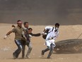 Palestinian protestors carry a wounded comrade during a protest near the border fence with Israel east of Jabalia in the central Gaza Strip on May 15, 2018. Palestinians were gathering today for fresh protests along the Gaza border, a day after Israeli forces killed dozens there as the US embassy opened in Jerusalem on what was the conflict's bloodiest day in years.