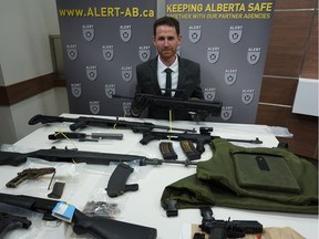 Alberta Law Enforcement Response Teams spokesman Mike Tucker with the firearms, including assault rifles, suppressors, and over-capacity magazines, that were seized as the result of an ALERT investigation in Edmonton and Fort McMurray.