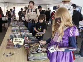 (Left to right) The Dompe family, including father Brad, son Ryan, 8, and daughter Mara, 11, grab free comics in the tent at Free Comic Book Day at Happy Harbor Comics in Edmonton, on Saturday, May 5, 2018. Mara dressed up in a Tangled dress with Star Wars glasses for the event. Photo by Ian Kucerak/Postmedia