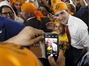 Prime Minister Justin Trudeau (centre) meets Gurdwara Millwoods congregants where he donated food to Edmonton's Food Bank, prayed and fed temple members in Edmonton, on Monday, May 14, 2018.