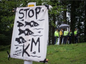 RCMP officers gather nearby as protesters opposed to the Kinder Morgan Trans Mountain Pipeline expansion defy a court order and block a gate at the company's facility, in Burnaby, B.C., on Saturday April 28, 2018.