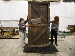 Royal Alberta Museum curator of Western Canadian history Julia Petrov, left, and museum public affairs officer Kelsie Tetreau move the front door of the 1928 Minchau Blacksmith Shop in Edmonton on Friday, June 1, 2018. The door is currently in one of the museum's storage warehouses for oversized objects.