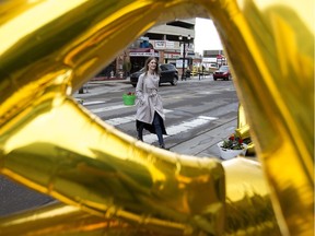 Chelsea Whitty is framed by giant gold balloons as she uses a crosswalk near 104 Street and 102 Avenue in Edmonton on Friday, June 1, 2018.