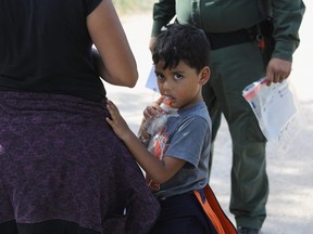 A two-year-old Honduran asylum seeker cries as her mother is searched and detained near the U.S.-Mexico border in McAllen, Texas.