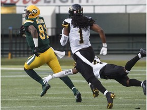 Hamilton Tiger-Cats Don Unamba (1) and Richard Leonard (4) try to catch Edmonton Eskimos D'haquille Williams (81) during first half CFL action in Edmonton, Alta., on Friday June 22, 2018.