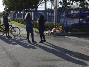 Fans and mourners of rap singer XXXTentacion pause by a memorial, Tuesday, June 19, 2018, outside Riva Motorsports in Deerfield Beach, Fla., where the troubled rapper-singer was killed the day before. The 20-year-old rising star, whose real name is Jahseh Dwayne Onfroy, was shot outside the motorcycle dealership on Monday, June 18, when two armed suspects approached him, authorities said.