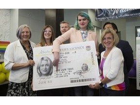 Quinn L. Nelson, a non-binary student from Calgary, points to a new gender marker on a driver's licence during a news conference with  MLA Maria Fitzpatrick, left. Service Alberta Minister Stephanie McLean, Strathcona Registry president Scott Mather, Culture Minister Ricardo Miranda and Premier Rachel Notley after announcing important changes to driver's licences and identity documents that support transgender and gender-diverse Albertans on Friday, June 8, 2018 in Edmonton.