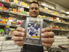 Wayne Wagner, owner of Wayne's Sports Cards in west Edmonton, holds a Connor McDavid Young Guns rookie card, while speaking about the recent sale of a rare Connor McDavid The Cup rookie card which sold online for more than $55,000, at his shop on Tuesday.