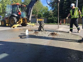 Epcor crews test the ground under Stony Plain Road and 146 Street Monday afternoon after a water main broke earlier that day.