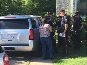 Police officers speak to a medical examiner outside a home where a body was discovered, near 106 Street and 65 Avenue.