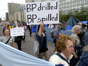 A woman holds a sign criticizing British Petroleum during a protest organized by the Council of Canadians against the Kinder Morgan pipeline, in Ottawa on Saturday, June 23, 2018. BP reported a drilling mud spill from the West Aquarius drilling unit in Nova Scotia on Friday.