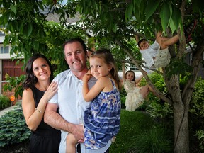 Patrick and Jacquelyn Mitchell hold their daughter, Hana, who was born during the flood of 2013. Twins Hunter and Halle, 7, play in the tree outside their restored home in Elbow Park on June 3, 2018.