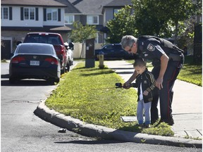 Ottawa Police Service Sgt. Randy Stockdale does a little fishing with Fadel Gouni on White Alder Avenue in Ottawa on Monday.