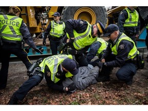 Dan Wallace, of the Kwakwaka'wakw First Nation on Quadra Island, is tackled and handcuffed by RCMP officers after attempting to talk to a young man that locked himself to a piece of heavy equipment being delivered to Kinder Morgan in Burnaby, B.C., on Monday March 19, 2018. Numerous protesters who blockaded an entrance — defying a court order — were arrested earlier in the day while protesting the Kinder Morgan Trans Mountain pipeline expansion.