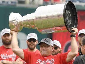 Washington Capitals head coach Barry Trotz raises the Stanley Cup as the team is honoured before a Washington Nationals game on June 9.