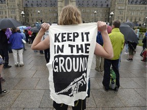 A protester holds a sign against fossil fuel development during a rally against the proposed Trans Mountain pipeline project, on Parliament Hill in Ottawa on Tuesday, May 22, 2018.